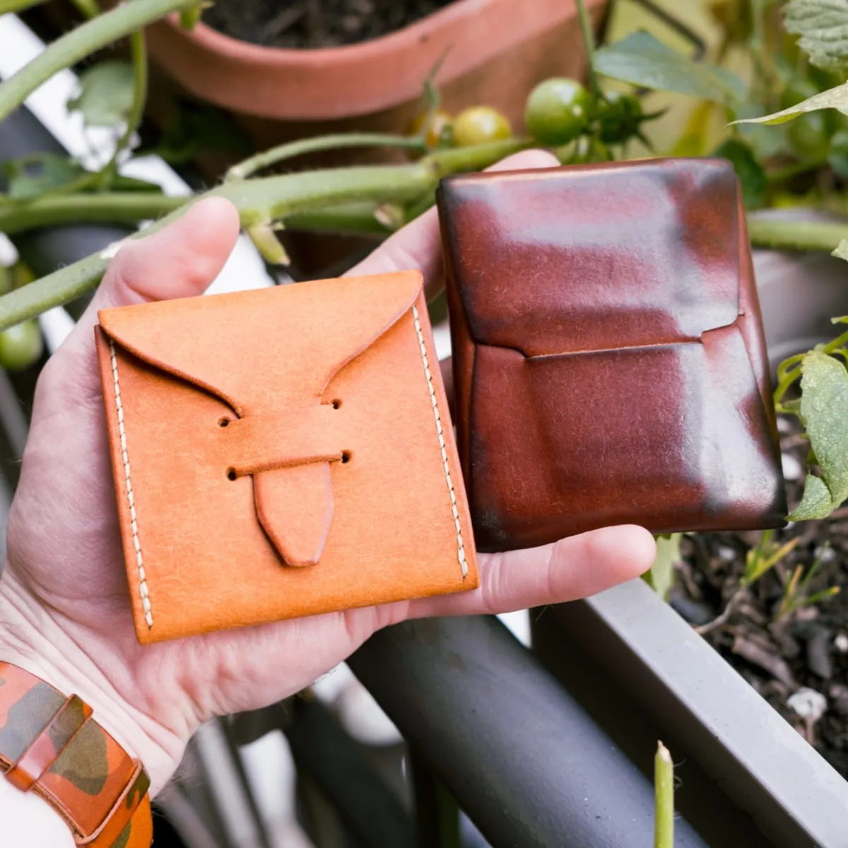 A new tan case held beside a well-used wallet in the same leather, now a glossy deep reddish brown, showing how far Pueblo darkens with use.